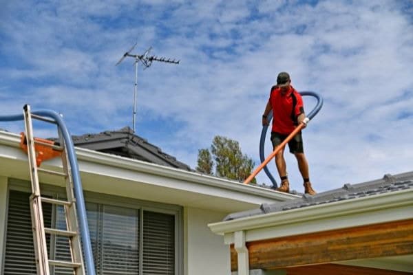 Propietario de vivienda limpiando los canales pluviales